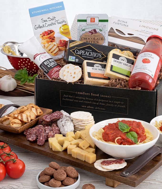 Gift ox with a box of grilled crostini toasta, jar of pasta sauce, blocks of garlic and vegetable cheese, sweet Soppressata, and chocoate bites. In front of the box is a grazing tray with crostini toasts, sliced Soppressata, cubed cheese, water crackers, 