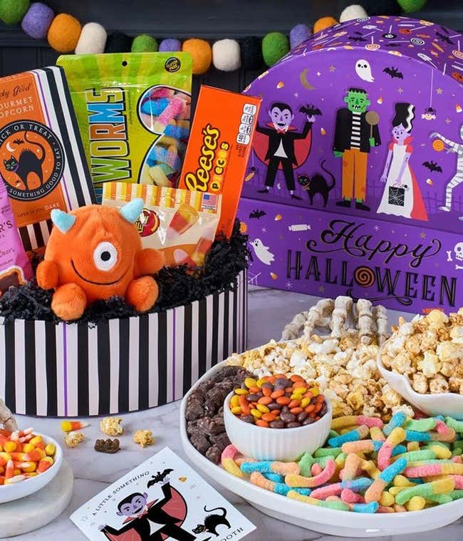 A gift box with a bag of dark chocolate cubetti, black &amp; white cookies, halloween crispy rice treat. bag of candy corn, bag of gummy worms, and a Tony's Chocolonely Bar. 