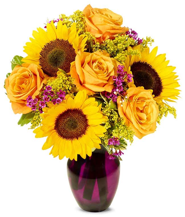  A vibrant floral arrangement featuring sunflowers, orange roses, pink wax flowers, and yellow solidago.