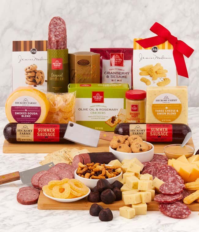 Charcuterie gift set with Hickory Farms summer sausages, smoked Gouda and three cheese &amp; onion cheeses, crackers, cookies, nut mix, dried fruit, mixed nuts, and chocolate-covered pretzels, arranged on a wooden board with cheese knives.