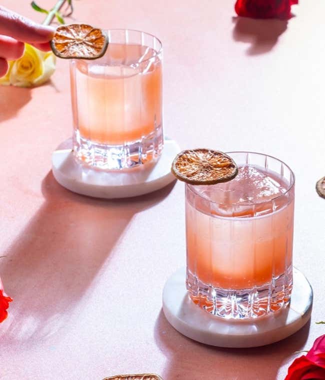 A gift box containing a 4oz bottle of pink tropical syrup, a 2 oz. bottle of super lemon-lime juice, a 3ml bottle of rose water, dehydrated lime wheels and a recipe card.