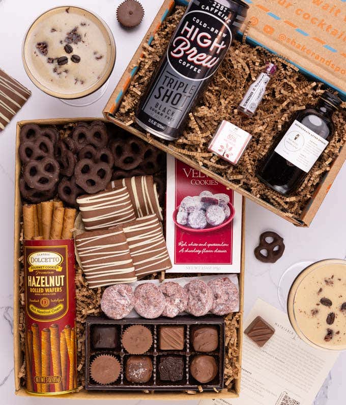 The sweets box contains a box of chocolates, chocolate pretzels & mini chocolate chip cookies.  The cocktail box contains a 4 oz. bottle of cherry-vanilla syrup, a mini bottle of bitters, a can of cold brew coffee, and a recipe card.