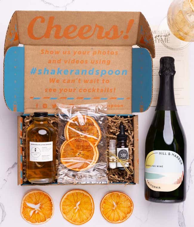 A bottle of Hill &amp; Harbor Sparkling Wine alongside a cocktail kit box containing thyme-cucumber syrup, celery bitters, grapefruit oil finishing mist, dehydrated grapefruit slices and a recipe card.