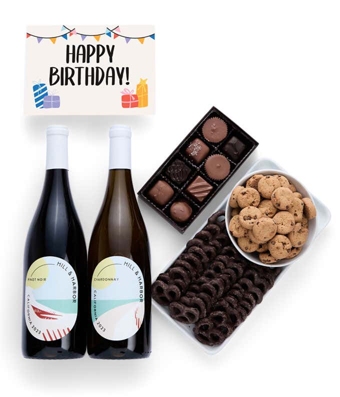 A gift box with chocolate pretzels, chocolate graham crackers, red velvet cookies, hazelnut wafer rolls, an 8 piece box of chocolates, 2 bottles of wine and a Birthday message card.