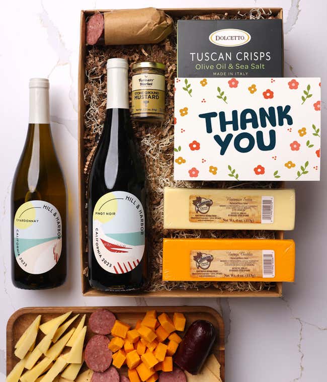 A gift box with two bottles of California wine (Pinot Noir and Chardonnay), two types of cheese, crackers, stone-ground mustard, a summer sausage, and a Thank You message card. 