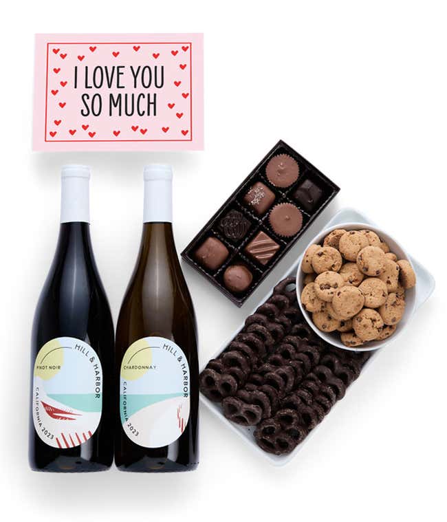A gift box with chocolate pretzels, chocolate graham crackers, red velvet cookies, hazelnut wafer rolls, an 8 piece box of chocolates, 2 bottles of wine and an I Love You message card.