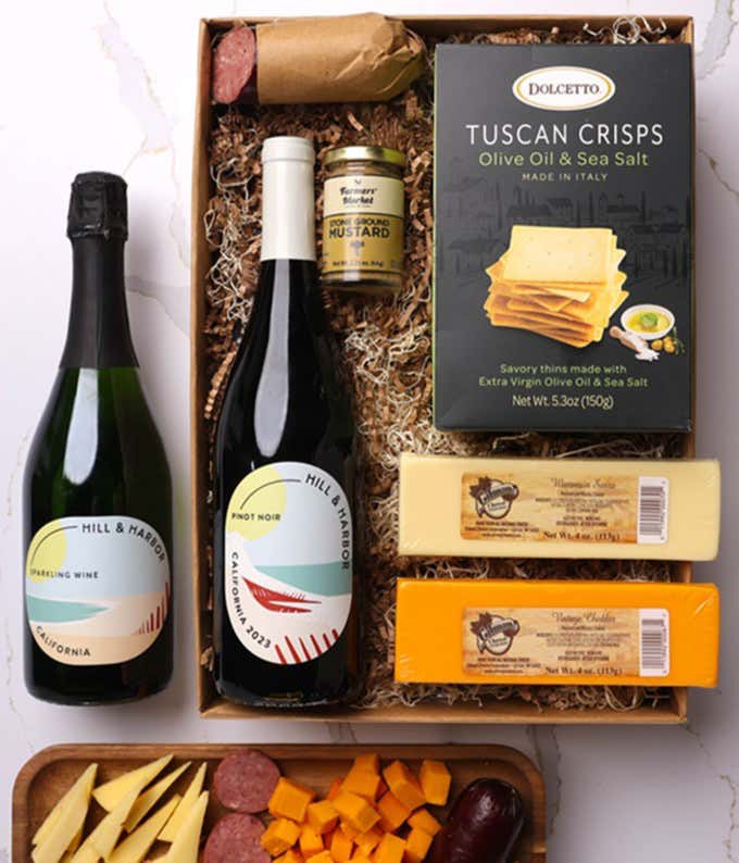 A gift box with two bottles of California wine - Pinot Noir and Sparkling Wine, two types of cheese, crackers, stone-ground mustard, and a summer sausage.
