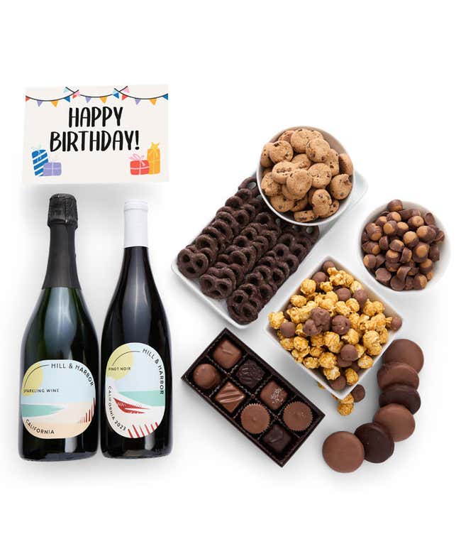 A gift box overflowing with treats including an assortment of chocolate-covered items like oreoes, almonds graham crackers and pretzels along with red velvet cookies, hazelnut wafers, an 8 piece box of chocolates, 2 bottles of wine and a Birthday card.
