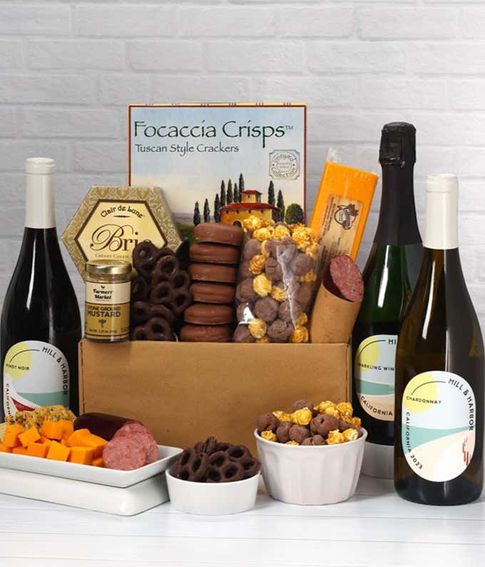 A gift set featuring a trio of California wines - red, white, and sparkling, focaccia crisps, 2 cheeses, mustard, summer sausage, caramel popcorn, chocolate pretzels, and 6 chocolate-covered Oreos for a sweet and savory gourmet experience.