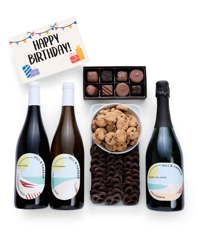 A gift box with chocolate pretzels, chocolate graham crackers, red velvet cookies, hazelnut wafer rolls, an 8 piece box of chocolates, 3 bottles of wine and a Birthday message card.