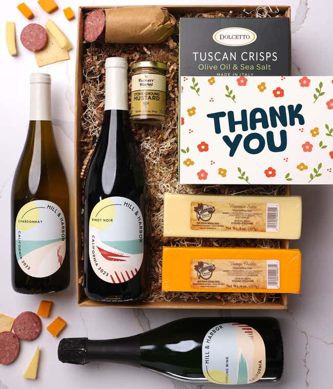 A gift box with three bottles of California wine (red, white, and sparkling), two types of cheese, crackers, stone-ground mustard, a summer sausage, and a Thank You message card.